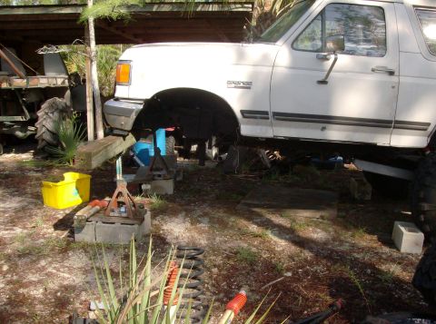 1989 Ford Bronco - White Ford Bronco, likely from the late 80s or early 90s, is elevated on jack stands for maintenance.