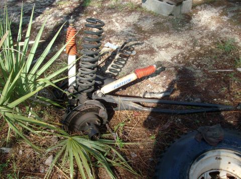1989 Ford Bronco - Front axle suspension components, including Fantech shocks and coil springs, are laid out on the ground.