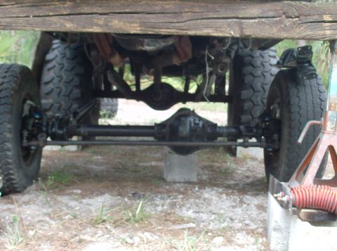 1989 Ford Bronco - The undercarriage of a 4x4 vehicle is visible, showing its solid axles and large tires.