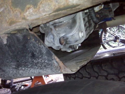 1995 Ford Bronco - Underside view of a vehicle's transmission, with a bicycle wheel visible in the background.