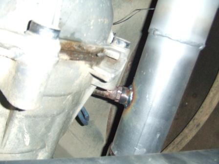 1996 Ford Bronco - Close-up under a vehicle of a metal bracket and large bolt near pipes and a crossmember.