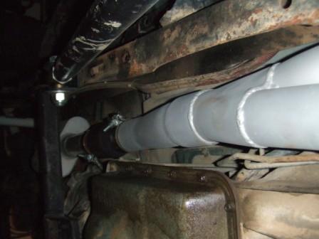 1996 Ford Bronco - Underbody view of exhaust pipes and driveshaft, with Supermotors logo.