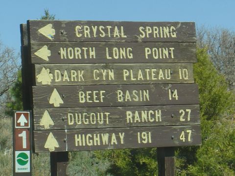 1986 Ford Bronco II - Wooden trail signs indicate directions and distances to various locations in a natural setting.