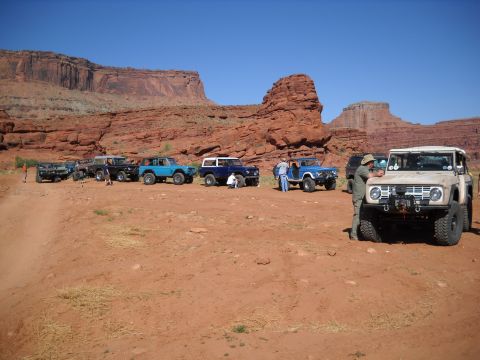 1986 Ford Bronco II - Several Ford Broncos are parked in a desert landscape under a clear blue sky.