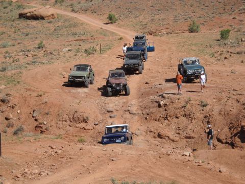 1986 Ford Bronco II - A convoy of SUVs, including a 1986 Ford Bronco II, navigates a desert trail.