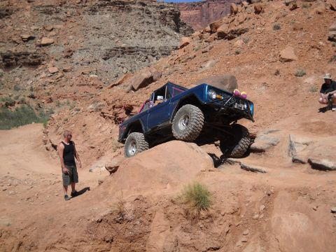 1986 Ford Bronco II - A blue off-road SUV navigates a rocky trail in a desert canyon landscape.