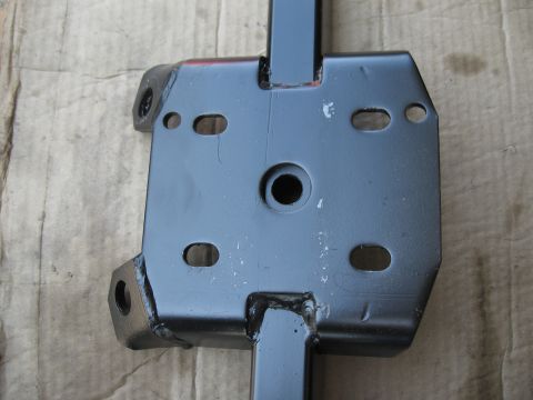 1968 Shelby GT500 - Close-up view of a black metal automotive part, likely a bracket or mount, with various holes for attachment.