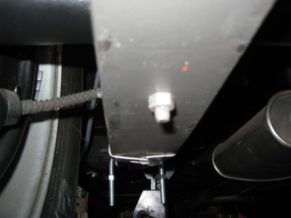 Close-up of Lakewood traction bars bolted to a car's undercarriage, near the exhaust pipe