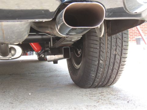 1968 Shelby GT500 - Close-up view of a vehicle's rear suspension system, red shock absorbers and a prominent exhaust pipe.