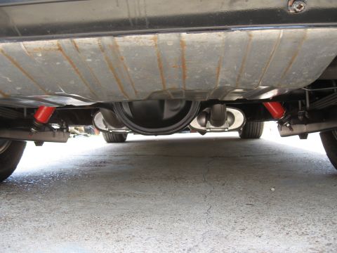 1968 Shelby GT500 - Rear axle and suspension parts, including red traction bars, are visible from underneath a vehicle.