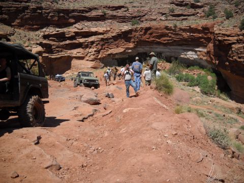 1986 Ford Bronco II - Several off-road vehicles navigate a challenging rocky terrain, with a group of people walking along the path.
