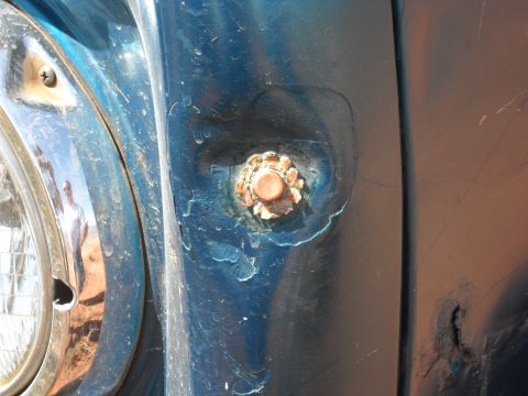1986 Ford Bronco II - Close-up of a blue vehicle's fender shows a rusty bolt and part of the headlight trim.