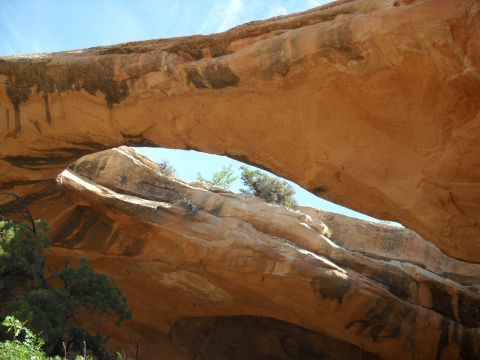 1986 Ford Bronco II - A natural sandstone arch frames a clear blue sky, with sparse vegetation clinging to the rock.
