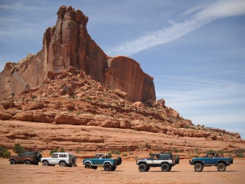 1986 Ford Bronco II - Four 1986 Ford Bronco IIs are parked in a desert landscape with large red rock formations.