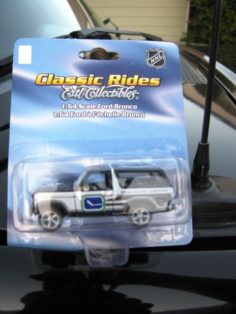 1986 Ford Bronco - A 1:64 scale Ford Bronco diecast model is displayed in its packaging on a dark surface.