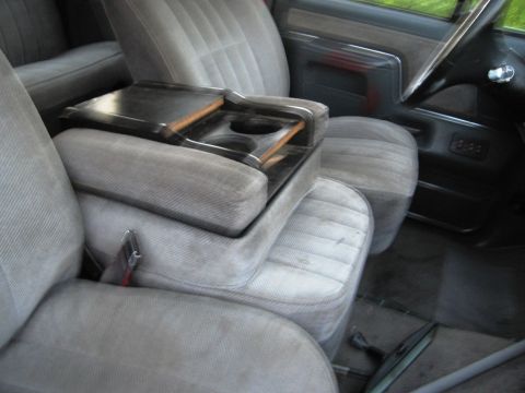 1986 Ford Bronco - Interior view of gray cloth seats and a center console with cup holders, consistent with a 1986 Ford Bronco.