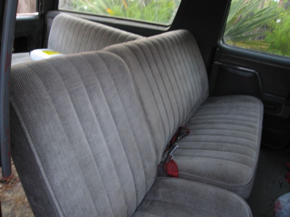 Gray fabric seats inside a vehicle with a red seatbelt visible