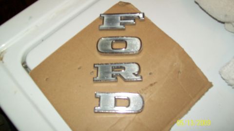 1972 Ford Ranchero - Individual chrome letters spelling out FORD are laid out on a piece of cardboard.