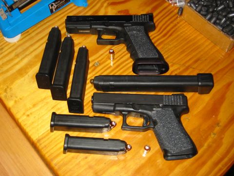 1996 Ford Bronco - A collection of handguns, magazines, and ammunition is laid out on a wooden table, suggesting preparation for shooting.