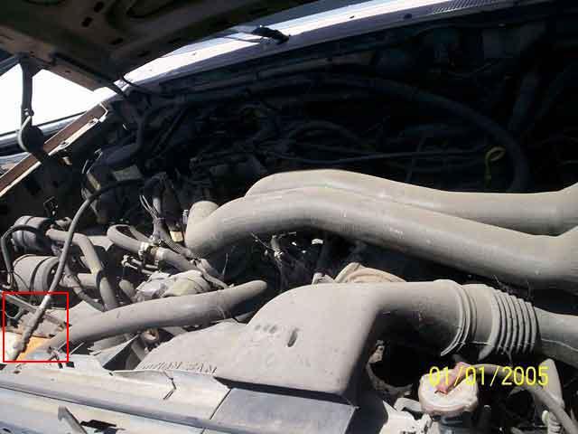 Dusty truck engine bay with a red box marking a part, dated 2005