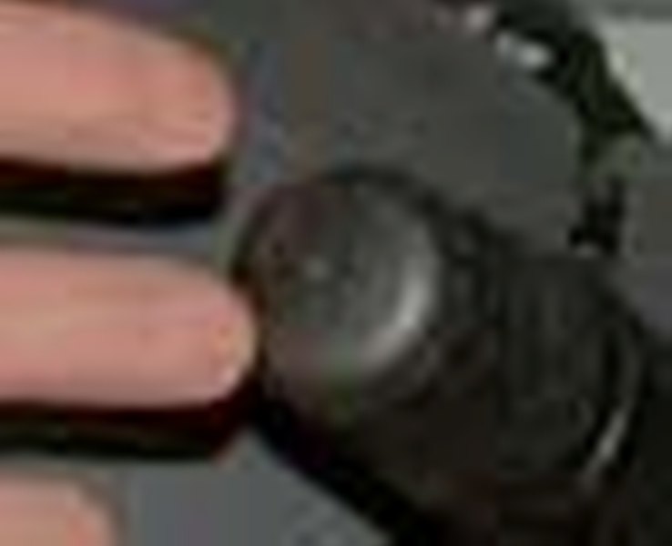 Close-up of a dark vehicle interior with a finger touching a round dial