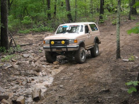1979 Ford F-150 - This tan Ford Bronco is equipped for off-road adventures, tackling a challenging muddy path through the woods.