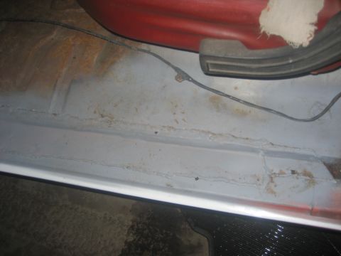 1983 Ford F-250 - Close-up view of the interior floor and lower seat area of a vehicle, showing signs of wear and wiring.