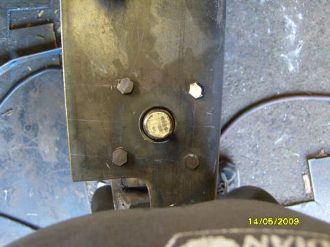 1989 Ford Bronco - Metal bracket with multiple bolts and a central fastener, likely a vehicle part.