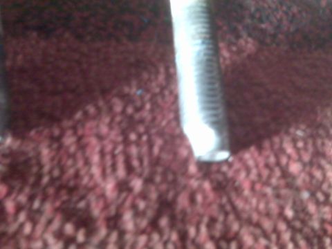 2008 Jeep Wrangler - A single metal bolt is visible against a textured red carpet background.