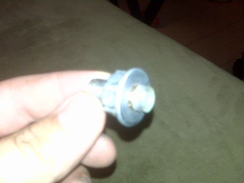 2008 Jeep Wrangler - A bolt with a washer is held in a hand, against a textured background.