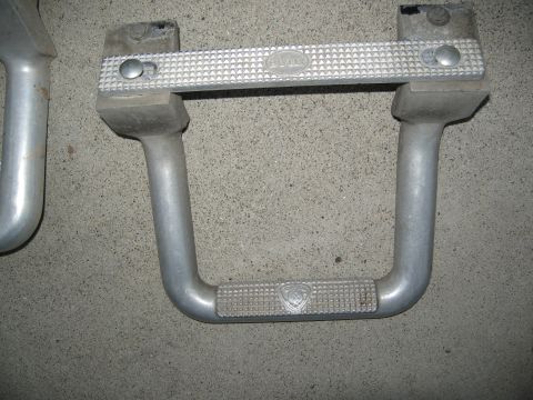 1986 Ford Bronco - Aluminum step bars with embossed logos are shown against a concrete surface.