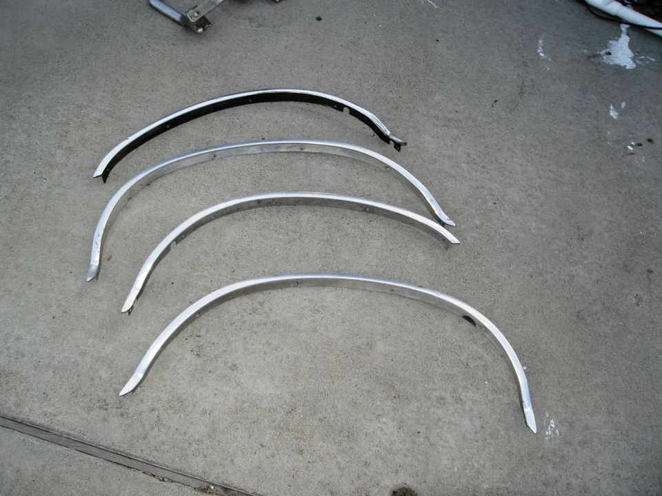 four curved metal trim pieces for wheel wells on concrete