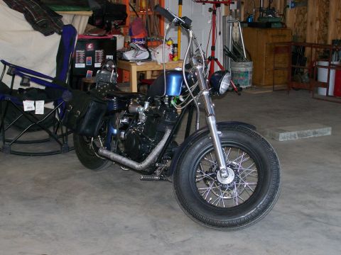 1988 Suzuki Samurai - Custom motorcycle with a blue fuel tank and chrome exhaust pipes parked indoors.