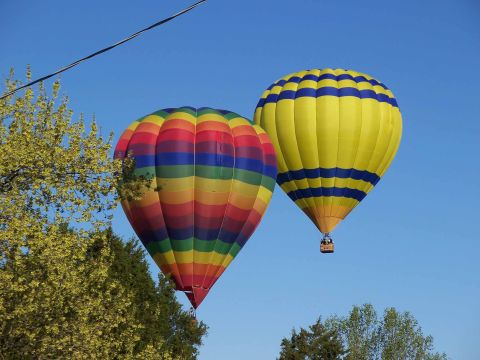 1971 Ford Ranchero - A vibrant rainbow-striped hot air balloon floats alongside a yellow and blue striped balloon under a clear blue sky.