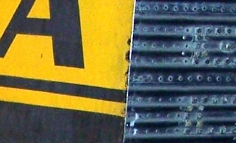 1971 Ford Ranchero - Close-up of a yellow sign and a textured metal surface with a watermark for Supermotors.net.