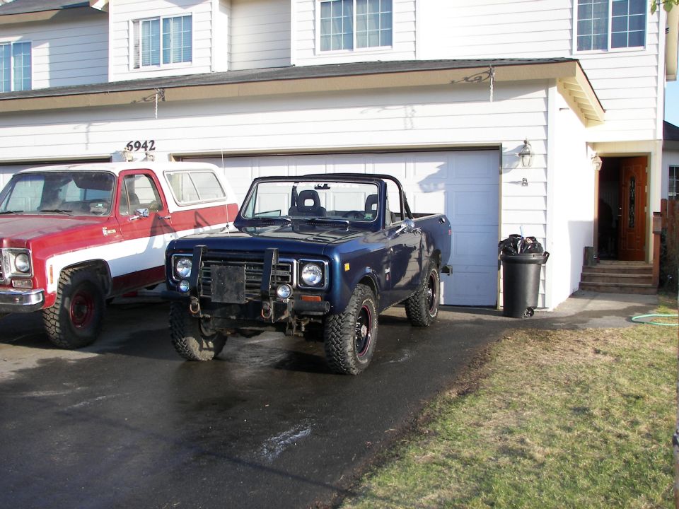 Blue convertible SUV parked in driveway next to a red and white pickup truck
