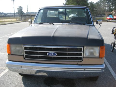 1983 Ford F-250 - This early 1980s Ford F-Series truck features a two-tone paint scheme with a dark blue cab and tan lower body panels.
