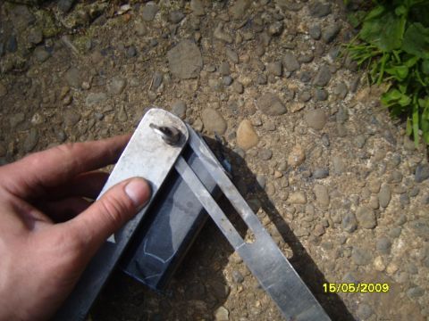 1989 Ford Bronco - A hand holds a metal angle finder tool over a gravel surface with some green foliage visible.