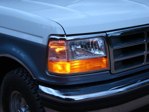 1995 Ford Bronco - Close-up of the front headlight and grille assembly on a 1995 Ford Bronco, with the amber turn signal lit.