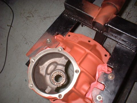 1970 Ford Torino - A close-up view of an orange transmission housing secured in a black metal jig, with a bearing visible inside.