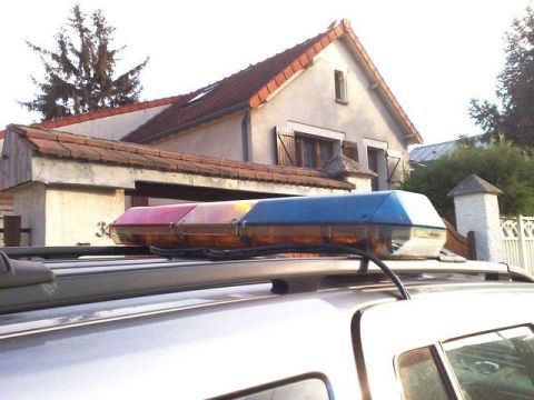1991 Ford Crown Victoria - A light bar with red, amber, and blue sections is mounted on the roof of a vehicle, with a house in the background.