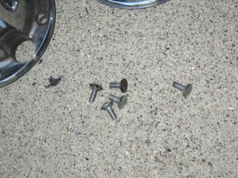 1986 Ford Bronco - A close-up of a vehicle hubcap and loose screws resting on a concrete surface.
