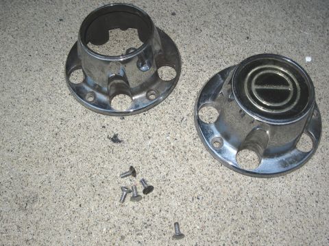 1986 Ford Bronco - Two chrome hubcaps and screws are shown on a concrete surface.