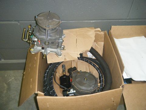 1978 Ford Bronco - A carburetor and fuel pump assembly with hoses are shown inside a cardboard box.