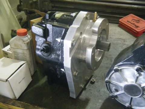 1978 Ford Bronco - A transfer case with an aluminum adapter plate and a splined output shaft is shown on a workbench. Another similar part is visible to the r…