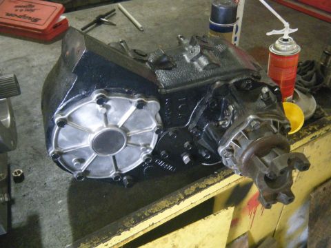 1978 Ford Bronco - A black transfer case sits on a workbench, with tools and spray cans visible in the background.