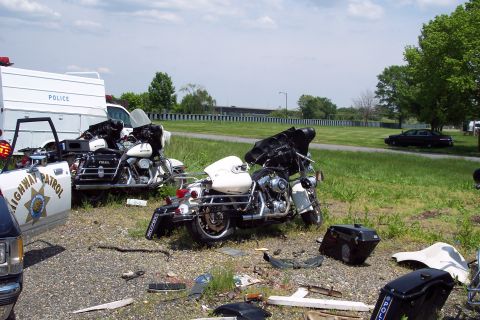 2001 Ford Crown Victoria - Damaged police motorcycles and a van are visible at a scene with scattered debris and a dark sedan in the background.