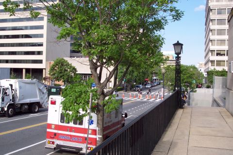 2001 Ford Crown Victoria - An ambulance and a garbage truck are seen on a street in a city environment.
