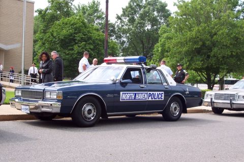 2001 Ford Crown Victoria - A dark blue police car with "NORTH HAVEN POLICE" text and a light bar is parked next to another vehicle.