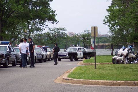 2001 Ford Crown Victoria - Several police vehicles, including cars and motorcycles, are gathered near a body of water.